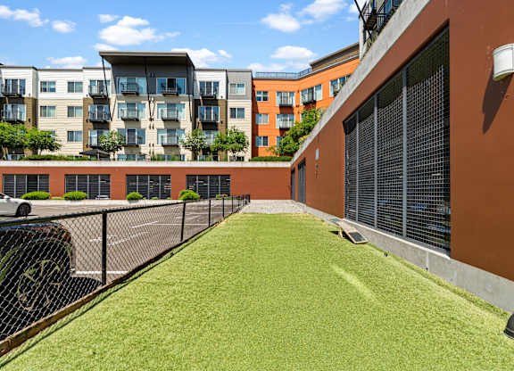 A grassy area in front of a building with a black car parked on the left side.
