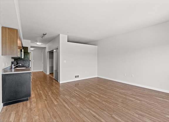 A kitchen with a black refrigerator and wooden floors.