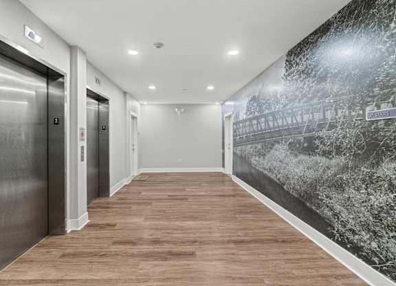 A hallway with wood floors and a wall mural of a bridge.