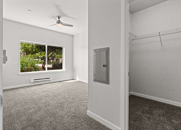 A room with a window, a fan, and a closet.