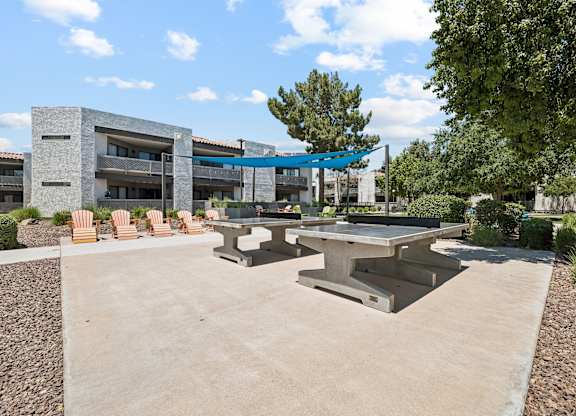 A concrete patio with a table and chairs in front of a building.
