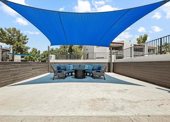 A blue shade structure is over a table and chairs.