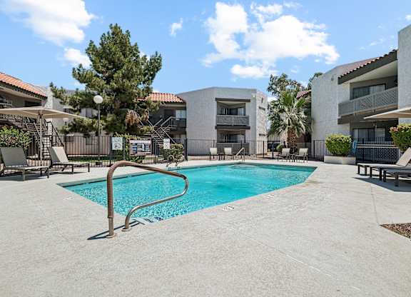 A swimming pool in a residential area surrounded by buildings and trees.