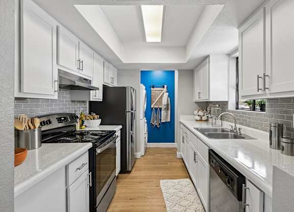 A modern kitchen with white cabinets and a black stove top oven.