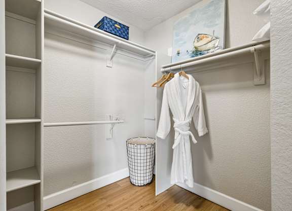 A white robe is hanging on a hanger in a white closet.