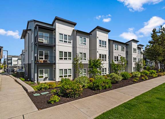 A row of modern townhouses with landscaped gardens in front.