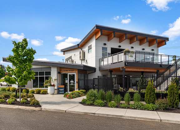 A modern building with a white and brown exterior and a black fence.