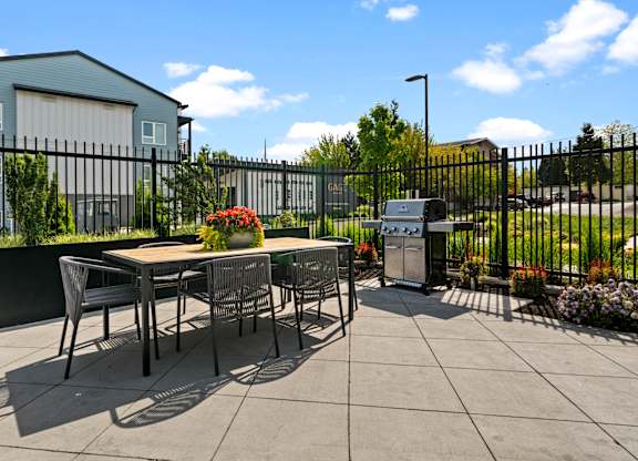 A patio with a table and chairs is surrounded by a black fence.