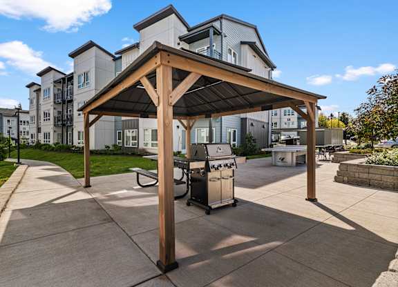 A wooden pavilion with a trash can underneath it.