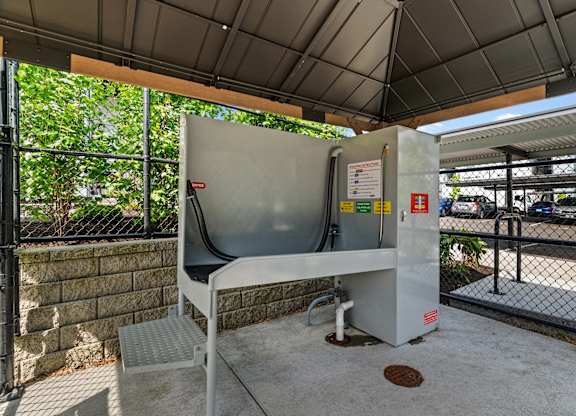 A white and grey portable toilet with a grey seat and a white pipe on the ground.