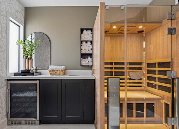 A modern kitchen with a black fridge and a wooden bench.