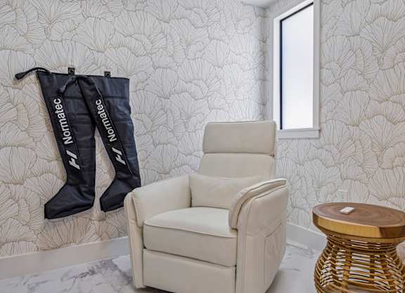 A chair and two boots are hanging on a wall.