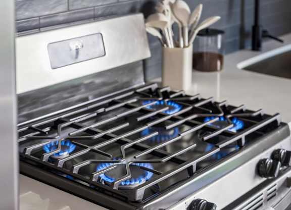 A modern gas stove with blue flames is in a kitchen.