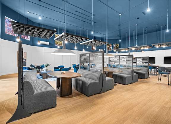 A room with a blue ceiling and wooden floors has a variety of seating options.