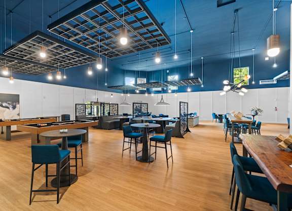 A room with tables and chairs and a pool table.