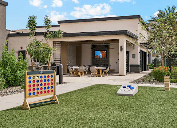 A backyard with a lawn, a table and chairs, and a giant checkerboard.