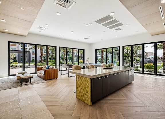A modern kitchen with a long island and lots of windows.