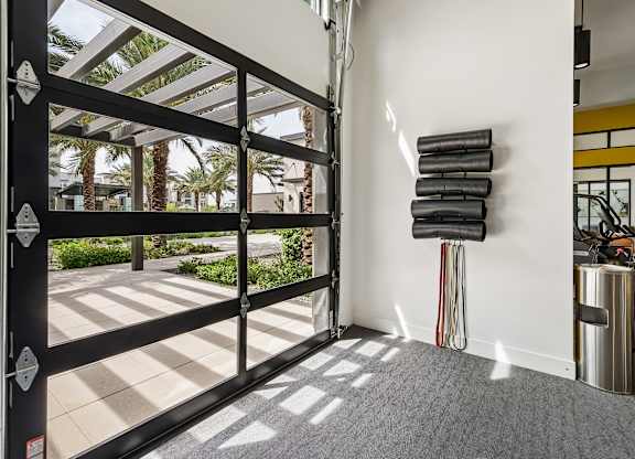 A black gate with a white stripe is open to a patio with palm trees.