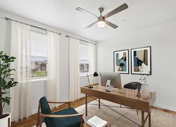A room with a desk, chair, and a ceiling fan.