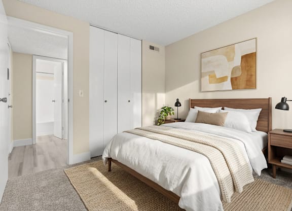 A bedroom with a large bed and a rug on the floor.