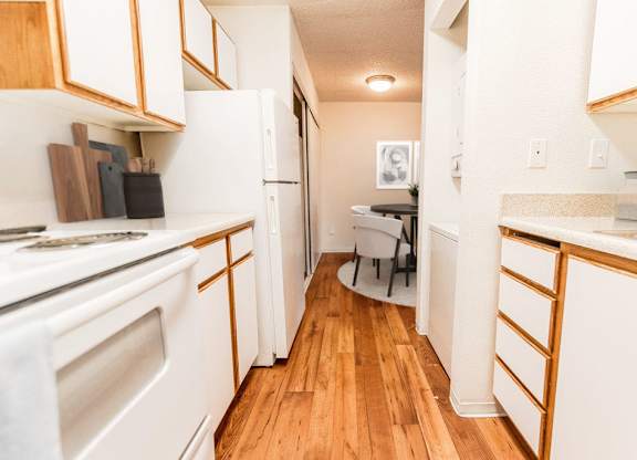 A kitchen with white appliances and wooden cabinets.