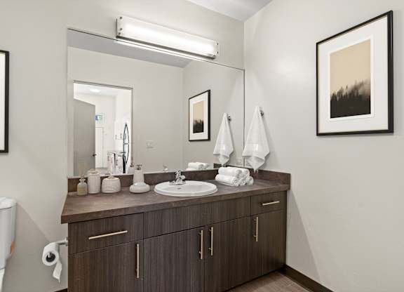 A bathroom with a white toilet and a brown vanity with a white sink.