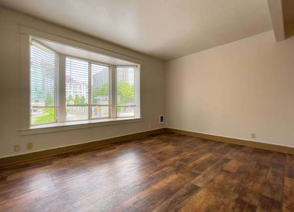 A room with wooden floors and a large window with blinds. at Zindorf, Seattle, WA
