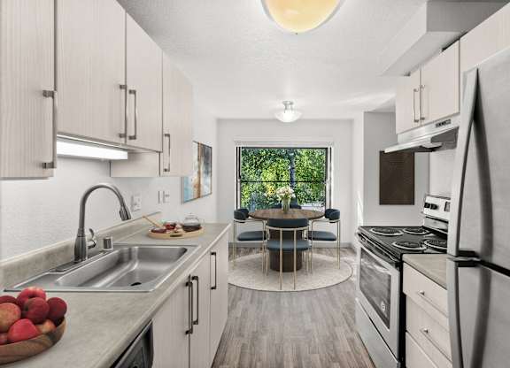 A modern kitchen with a dining table and chairs in the middle.