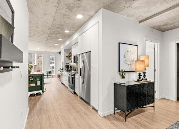 A modern kitchen with white walls and wooden floors.