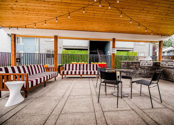 A patio with a striped couch and a table with chairs.
