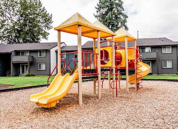 A playground with a yellow slide and a red and yellow structure.