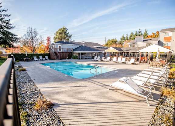 A pool area with sun loungers and a building in the background. at Northpoint Apartments, Tacoma, WA, 98407