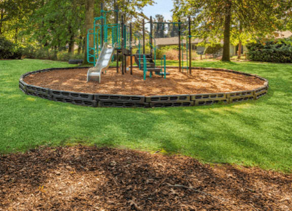 A playground with a green slide and a brown sandbox. at The Retreat, Sumner, WA