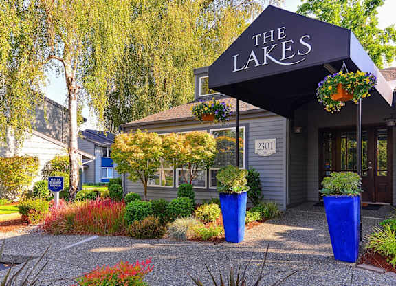 The Lakes building has a black awning and is surrounded by blue planters. at The Lakes at Fife, Fife, WA