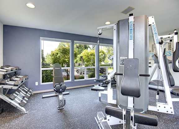 A home gym with a variety of equipment including a squat rack, bench press, and a rowing machine. at The Lakes at Fife, Fife, WA, 98424