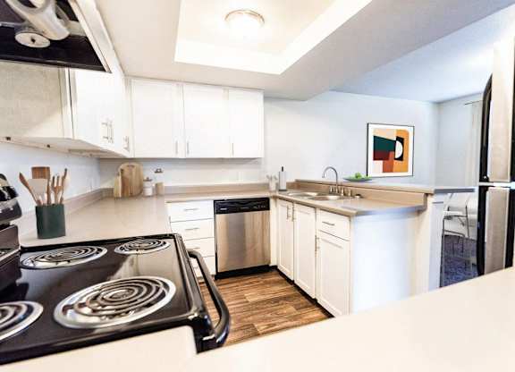 A modern kitchen with a stove top oven and white cabinets.