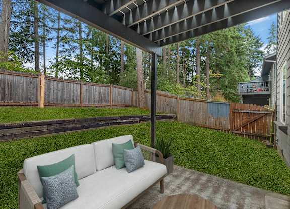 A white couch with two green pillows sits on a wooden deck.