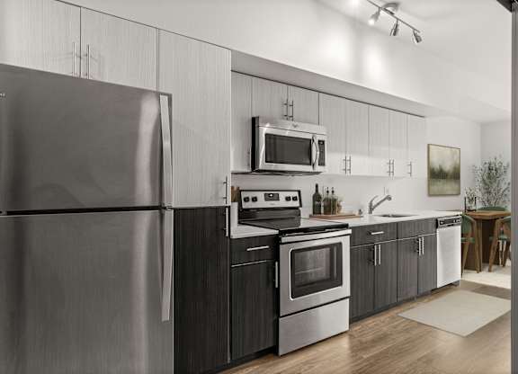 A modern kitchen with a stainless steel refrigerator and black cabinets.