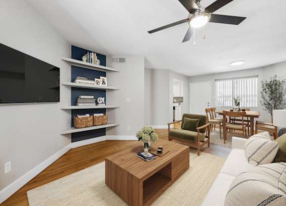 A living room with a wooden coffee table and a flat screen TV mounted on the wall.