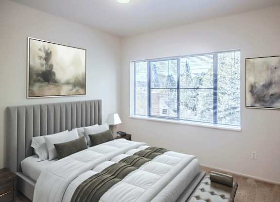 A bedroom with a large bed and two framed pictures on the wall.