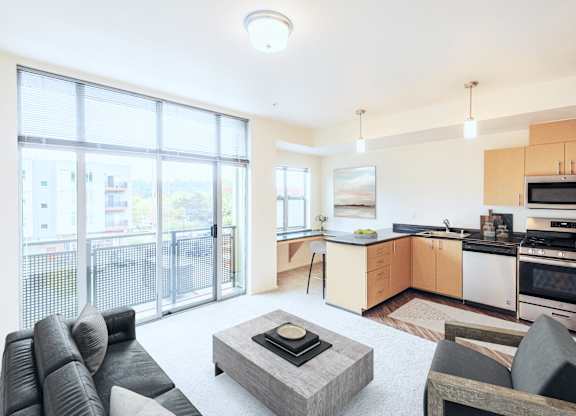 A modern living room with a grey sofa, a coffee table, and a kitchen area in the background.