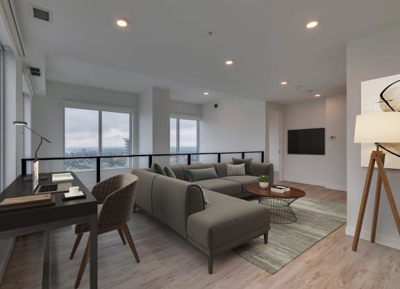 a living room with a gray couch and a desk and a television at BLVD Beltline, Calgary, AB