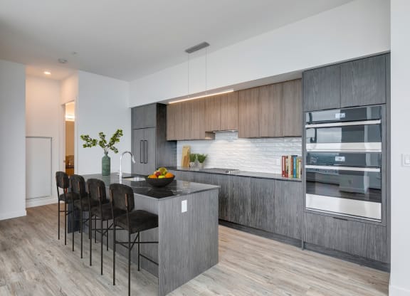 a modern kitchen with a large island with a counter top and chairs at BLVD Beltline, Calgary, AB