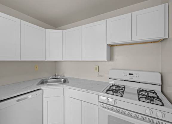 A white kitchen with a stove, sink, and cabinets at Kensington House, Kensington, Maryland