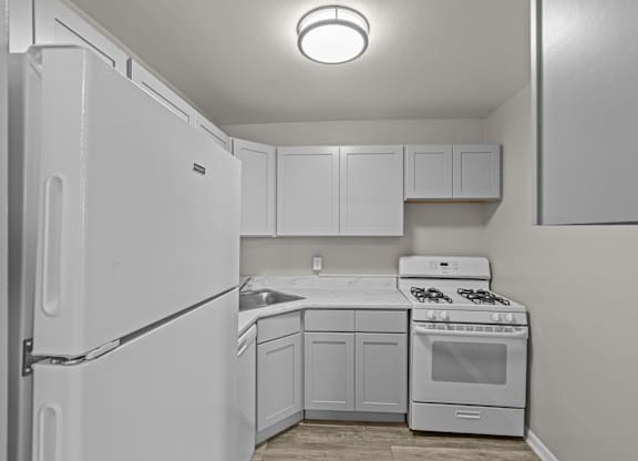 A white kitchen with a refrigerator, sink, stove, and cabinets at Kensington House, Maryland