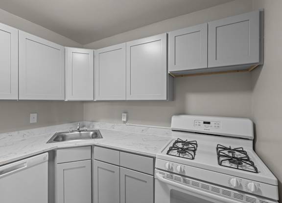 A kitchen with white cabinets and a white stove top oven at Kensington House, Kensington