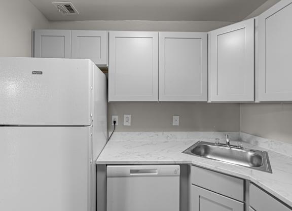 A white refrigerator is in a kitchen with a white counter top at Kensington House, Kensington, Maryland