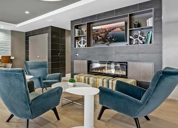 A modern living room with a fireplace and blue chairs.