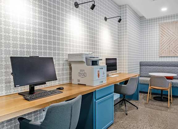 A room with a desk, chairs, and a sofa.