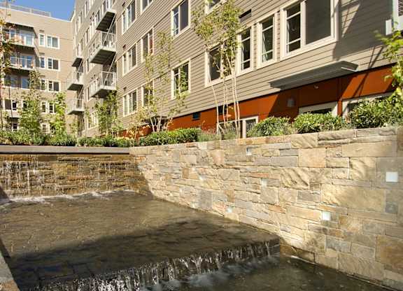 A small waterfall in a courtyard surrounded by buildings.